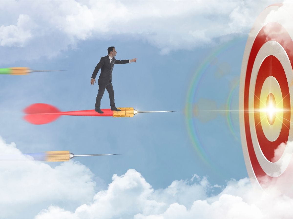 A man riding a dart aiming for the bullseye on the target
